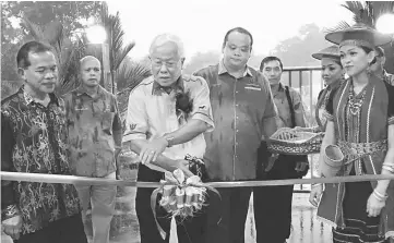  ??  ?? Manyin (centre) cuts a ribbon to officially declare open the church building extension, as organising chairman Boni Dowel (left) and others look on.