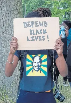  ?? /Kate Bartlett ?? Dismay over SA: A protester in a Mandela T-shirt hides her face at an antiracism rally in Oxford. South Africans at the rally expressed their dismay over state violence during the lockdown in SA.