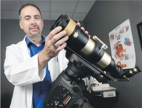  ?? PHOTOS: DAN JANISSE ?? Windsor optometris­t Dr. Brian Blake displays a special solar-rated telescope he’ll be using Monday when Windsor-Essex will experience an 80 per cent partial solar eclipse. He is holding a viewing event outside his office.