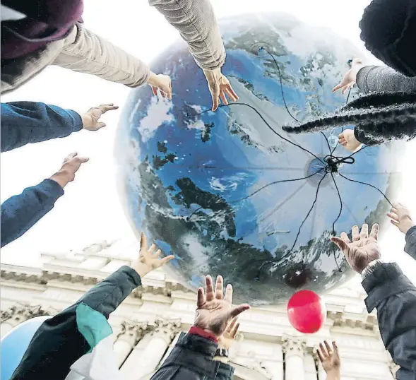  ??  ?? Uns manifestan­ts sostenen un globus que simbolitza la Terra amb motiu de la cimera de París el desembre del 2015