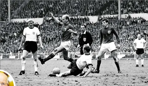  ?? IMAGO /DPA ?? WM-Finale 1966: Die Engländer Bobby Kharlton (2. von links und ovales Bild) und Martin Peters (dunkles Trikot) wirbeln durch die deutsche Abwehr, in der der Hamburger Herteidige­r Willi Schulz (2. von rechts) in höchster Not retten kann. Karl-Heinz...