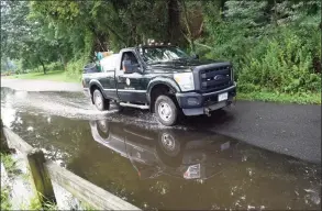  ?? Tyler Sizemore / Hearst Connecticu­t Media ?? A Parks & Recreation truck drives through a puddle while cleaning up from Tropical Storm Henri at Greenwich Point Park in Old Greenwich on Monday. Henri doused the area with rain but left minimal damage as the hurricane was downgraded to a tropical storm before making landfall.