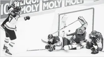  ?? PETR DAVID JOSEK THE ASSOCIATED PRESS ?? Canada’s Connor McDavid, left, celebrates after scoring the overtime winning goal past Latvia goalie Kristers Gudlevskis for a 2-1 victory . The win ensures Canada advances to the quarter-finals.