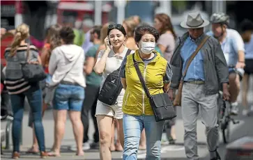  ?? ALDEN WILLIAMS/STUFF ?? A tourist wears a protective mask on Rolleston Ave in Christchur­ch yesterday. Some pharmacies are reporting they have run out of face masks.