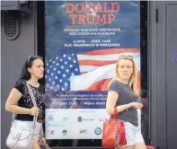  ?? ALIK KEPLICZ/AP ?? Two women in Warsaw, Poland, walk by a poster advertisin­g U.S. President Donald Trump’s upcoming visit. The poster reads “Donald Trump: First Public Appearance in Europe.”