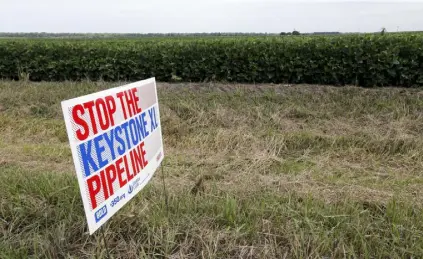  ?? Nati Harnik, AP file photos ?? In this July 29, 2017, photo, a sign reading: “Stop the Keystone XL Pipeline” sits in the proposed path of the Keystone XL pipeline, in Silver Creek, Neb.