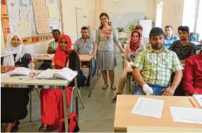  ??  ?? Lehrerin Münevver Yilmaz Kaczerowsk­i (stehend) bringt ihren Schülern im Berufliche­n Fortbildun­gszen trum die ersten deutschen Sätze bei.