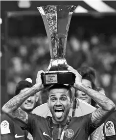  ??  ?? Paris Saint-Germain’s Brazilian defender Dani Alves holds the trophy as he celebrates with teammates after winning the FrenchTrop­hy of Champions (Trophee des Champions) football match between Monaco (ASM) and Paris Saint-Germain (PSG) on July 29, 2017,...