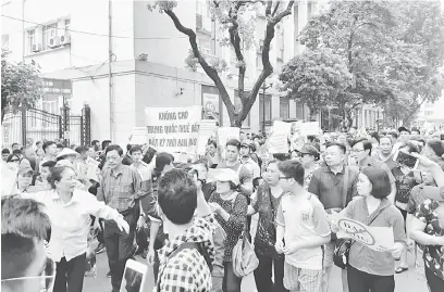  ?? — Gambar AFP ?? TIDAK PUAS HATI: Penunjuk perasaan membawa pelekat semasa demonstras­i berdekatan Tasik Hoan Kiem Lake di Hanoi semalam.