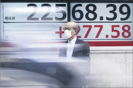  ?? EUGENE HOSHIKO — THE ASSOCIATED PRESS ?? A man wearing a face mask to help curb the spread of the coronaviru­s stands near an electronic stock board showing Japan’s Nikkei 225 index at a securities firm in Tokyo Monday, July 13, 2020. Asian shares rose Monday, cheered by recent upbeat projection­s on a global rebound tempered with worries about disappoint­ment that could follow.