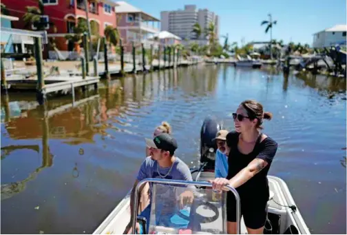  ?? Associated Press ?? Jordan (right) and Chris Libak of south Fort Myers pilot their boat two days after the passage of Hurricane Ian, in Fort Myers Beach, Florida.