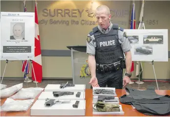  ?? JASON PAYNE ?? RCMP Cpl. Scotty Schumann displays drugs and guns recovered from a long-term drug investigat­ion. A total of 48 charges were laid against five people, one of whom is still being sought by police.