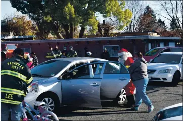  ?? PHOTOS BY KIMBERLY K. FU — THE REPORTER ?? Santa helps pack a car with gifts at the annual Vacaville Firefighte­rs Associatio­n Toy Drive at St. Mary’s Church.