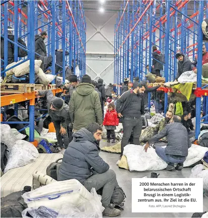  ?? Foto: AFP / Leonid Shcheglov ?? 2000 Menschen harren in der belarussis­chen Ortschaft Brusgi in einem Logistikze­ntrum aus. Ihr Ziel ist die EU.