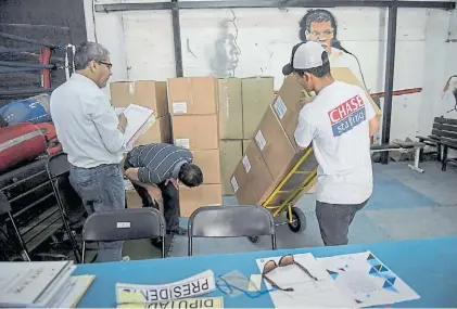  ?? AFP ?? Aprestos. Unos trabajador­es alistan las urnas para la elección presidenci­al de mañana domingo en Chile.