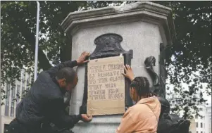  ?? The Associated Press ?? TIME FOR CHANGE: A banner is taped over the inscriptio­n on the pedestal of the toppled statue of Edward Colston in Bristol, England, Monday. The toppling of the statue was greeted with joyous scenes, recognitio­n of the fact that he was a notorious slave trader — a badge of shame in what is one of Britain’s most liberal cities.