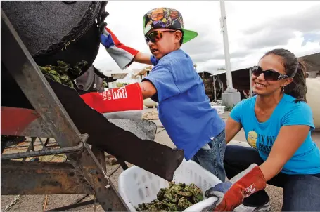  ??  ?? ABOVE: Chris Duran Jr., 7, helps roast green chile Tuesday with his family outside Big Lots on Cerrillos Road. RIGHT: Aaliyah Rose Duran, 8 months old, sits among bushels of fresh green chile Wednesday at her family’s stand, Los Chile Bros., outside...