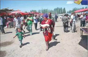  ??  ?? A woman heads home from the livestock market carrying a lamb she has purchased.