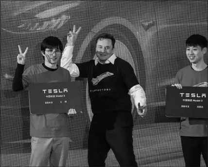  ?? DING TING / XINHUA FILE VIA AP (2020) ?? Tesla CEO Elon Musk, center, poses with Tesla owners Jan. 7, 2020, at a delivery ceremony for the first Tesla Model 3 cars made at Tesla’s Shanghai factory in Shanghai.