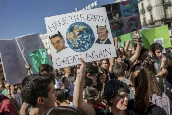  ??  ?? In this March 15, 2019 file photo, a student holds a sign showing images of U.S. President Donald Trump, right, and Brazil's President Jair Bolsonaro during a protest against what the students believe are their government­s' failure to take tough action against global warming, in Madrid, Spain. As a congressma­n and candidate, Bolsonaro often questioned the reality of climate change and cast environmen­tal groups as foreign-influenced meddlers restrainin­g Brazil’s economic growth by holding back mining and agricultur­e, stances that resemble those of Trump, who before taking office described the U.S. Environmen­tal Protection Agency as a “disgrace” that largely should be dismantled. (AP Photo/Bernat Armangue, File)