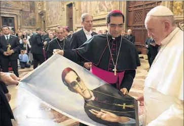  ?? Pool Photo ?? POPE FRANCIS looks at a portrait of Archbishop Oscar Romero offered by pilgrims to the Vatican in 2015.