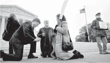  ?? Jacquelyn Martin / Associated Press ?? Rev. Brad Wells, left, Rev. Patrick Mahoney and Paula Oas pray Tuesday in front of the Supreme Court as a counterpro­tester holds a sign that reads, “What’s Christian About Discrimina­tion.”