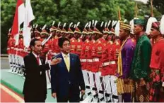  ?? AP ?? Indonesian President Joko Widodo and Japan PM Shinzo Abe inspect honour guard during a welcome ceremony at the Presidenti­al Palace in Bogor, West Java, yesterday.