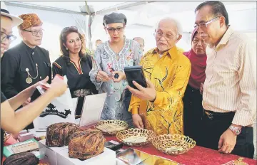  ??  ?? Taib takes a closer look at a traditiona­l Melanau accessory on display at one of the booths, set up for ‘Kuching Melanau Family Day 2017. On his left is Len.