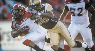  ?? JEFF MCINTOSH/ THE CANADIAN PRESS ?? Winnipeg Blue Bomber Kenny Tate tackles Calgary Stampeder Jock Sanders in Calgary on Saturday. Sanders ran fi ve times for 51 yards in the Stamps’ 23- 20 pre- season victory.