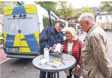  ?? RP-FOTO: HANS-JÜRGEN BAUER ?? Polizei kam mit dem Info-Mobil zur Aktion „Riegel vor“auf den Dr.-Franz-Schütz-Platz. Hauptkommi­ssar Jürgen Balzer berät ein Büdericher Ehepaar.