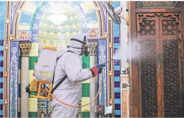  ?? FOTO: GEHAD HAMDY/DPA ?? Ein Mitarbeite­r trägt Schutzklei­dung, als er die Innenräume der Al-Sayeda-Nafeesah-Moschee in Kairo vor dem Fastenmona­t Ramadan desinfizie­rt.