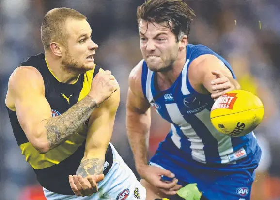  ?? Picture: GETTY ?? Richmond’s Brandon Ellis handballs while Luke McDonald of the Kangaroos closes in during the Round 11 AFL match at Etihad Stadium in Melbourne yesterday. The Tigers triumphed by 35 points