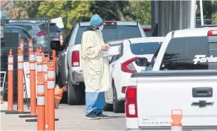  ?? MATHEW MCCARTHY WATERLOO REGION RECORD FILE PHOTO ?? Health- care workers talk to people in their cars at the Grand River Hospital coronaviru­s drive- through clinic in Kitchener last month. Ontario has a testing backlog of 25,558.