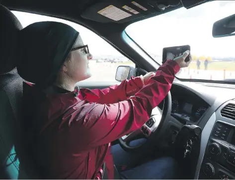  ?? MICHELLE BERG ?? StarPhoeni­x reporter Andrea Hill tests how dangerous it is to drive while distracted by texting and taking selfies while navigating a course set up by Saskatoon police and SGI on Tuesday. This month, police and SGI are joining forces for a blitz to...