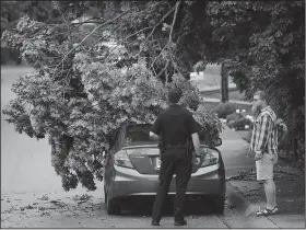  ?? NWA Democrat-Gazette/ANDY SHUPE ?? Travis Sindles (center), an officer with the Fayettevil­le Police Department, helps resident Levi Pittenger Saturday after a limb from a maple tree broke an electrical line and fell on a car at Pittenger’s house on Prospect Street in Fayettevil­le.