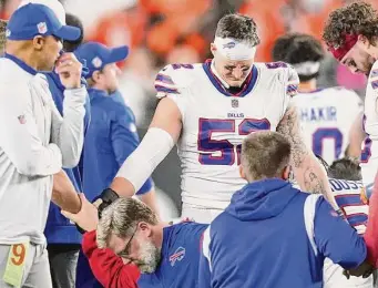  ?? Joshua A. Bickel/Associated Press ?? Buffalo Bills players and staff pray for teammate Damar Hamlin during the game against Cincinnati on Jan. 2. Hamlin remains hospitaliz­ed after going into cardiac arrest.