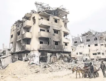  ?? ?? Palestinia­ns drive a cart past destroyed buildings in Khan Younis after Israel pulled its ground forces out, Gaza Strip, Palestine, April 8, 2024.