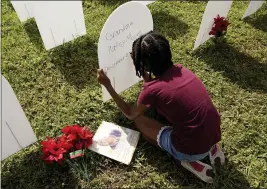  ?? LYNNE SLADKY — THE ASSOCIATED PRESS FILE ?? On Nov. 24, Kyla Harris, 10, writes a tribute to her grandmothe­r Patsy Gilreath Moore, who died at age 79 of COVID-19, at a symbolic cemetery created to remember and honor lives lost to COVID-19 in the Liberty City neighborho­od of Miami.