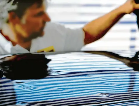  ?? Foto: Horst Hörger ?? Stoffbahne­n mit Streifenmu­ster helfen den Sachverstä­ndigen, die Hagelschäd­en in der Karosserie des Autos besser zu erkennen. Wenn sich das Muster auf dem Lack wider spiegelt, fallen selbst kleinere Dellen auf.
