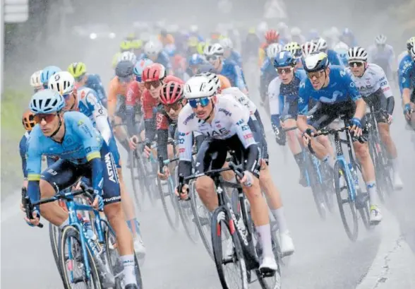  ?? Fotos: Iban Aguinaga ?? Un pelotón durante la bajada que se muestra golpeada por el temporal en el GP Miguel Indurain.