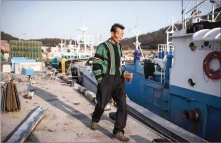  ?? ED JONES/AFP ?? A fisherman walks before boats at a small fishing port adjacent to Paengmok harbour on South Korea’s southern island of Jindo on March 21.