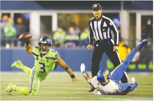  ?? LINDSEY WASSON/GETTY IMAGES ?? Seahawks QB Russell Wilson attempts to pass the ball while falling to the turf on Thursday night in Seattle. Bad enough that the Seahawks lost the game, 26-17 to a division rival, but they may also have lost their iron man pivot, who injured his throwing hand.