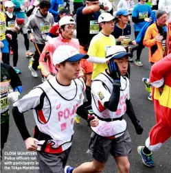  ??  ?? CLOSE QUARTERS Police officers run with participan­ts in the Tokyo Marathon