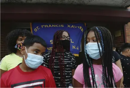  ?? Jessie Wardarski, The Associated Press ?? Malik Bey, 11, left, stands with his sisters in front of St. Francis Xavier School in Newark, N.J., on Thursday as parents meet to fight the school's permanent closure.