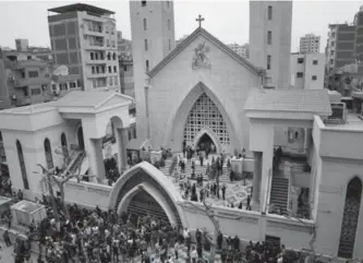  ?? NARIMAN EL-MOFTY, THE ASSOCIATED PRESS ?? People gather outside the St. George’s Church after a suicide bombing, in Tanta, Egypt, Sunday. Bombs exploded at two Coptic churches in Tanta and Alexandria as worshipper­s were celebratin­g Palm Sunday.