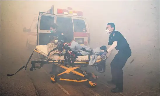  ?? Gina Ferazzi Los Angeles Times ?? PARAMEDICS TRANSPORT a resident from the Riverside Heights Healthcare Center in Jurupa Valley amid thick smoke as the Hill fire grew dangerousl­y close.