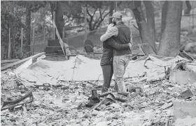  ?? Josh Edelson / AFP/Getty Images ?? Chris and Nancy Brown embrace while looking over the remains of their burned residence after the Camp Fire tore through the region in Paradise, Calif.
