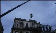  ?? (AP/Ramon Espinosa) ?? A crane lifts firefighte­rs in a cage toward a building in search of survivors after it partially collapsed on Wednesday in Havana, Cuba.