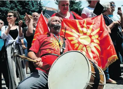  ?? MAJA ZLATEVSKA / AFP / GETTY IMAGES ?? A man plays drum next to a woman waving a Macedonian flag during a protest Sunday in Bitola after Greece and Macedonia signed a preliminar­y agreement to rename Macedonia.