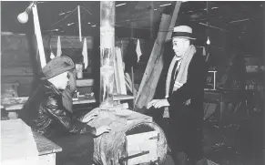  ?? — 2001.9.121/NIKKEI NATIONAL MUSEUM FILES ?? Two men warm their hands at an oil-drum stove in an uninsulate­d hut in Tashme.